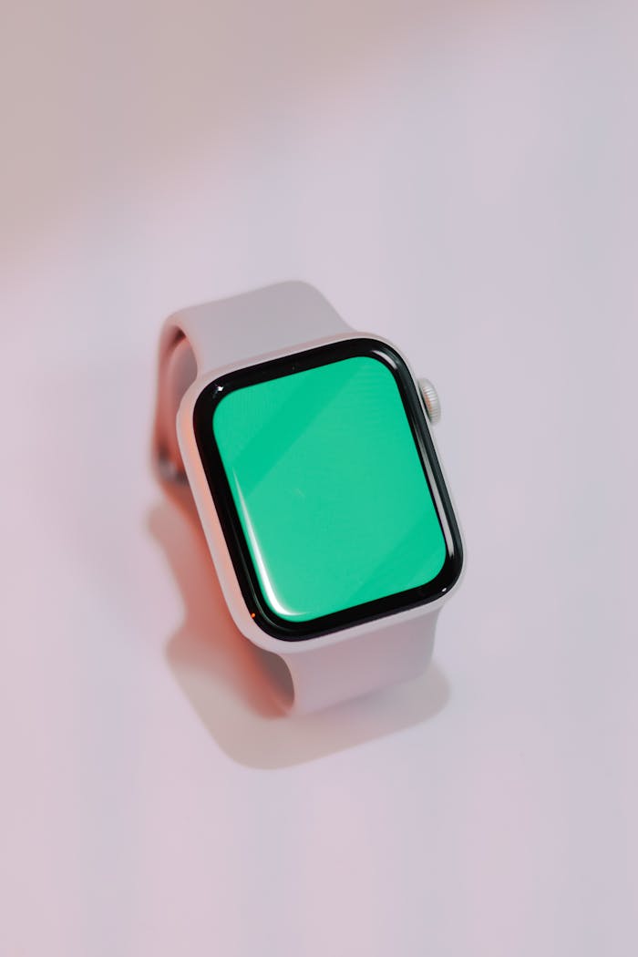 Close-up of a sleek smartwatch with a green screen, isolated on a light background.